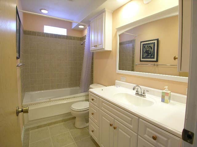 the bathroom has a generous vanity and mirror and features a shower with Jacuzzi tub.