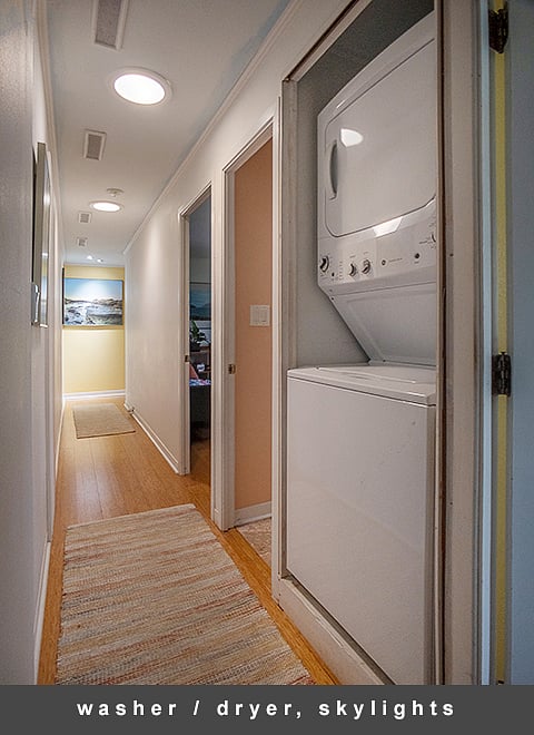 A stack washer / dryer makes laundry chores an in-house affair with a pair of skylights keeping the hallway bright.
