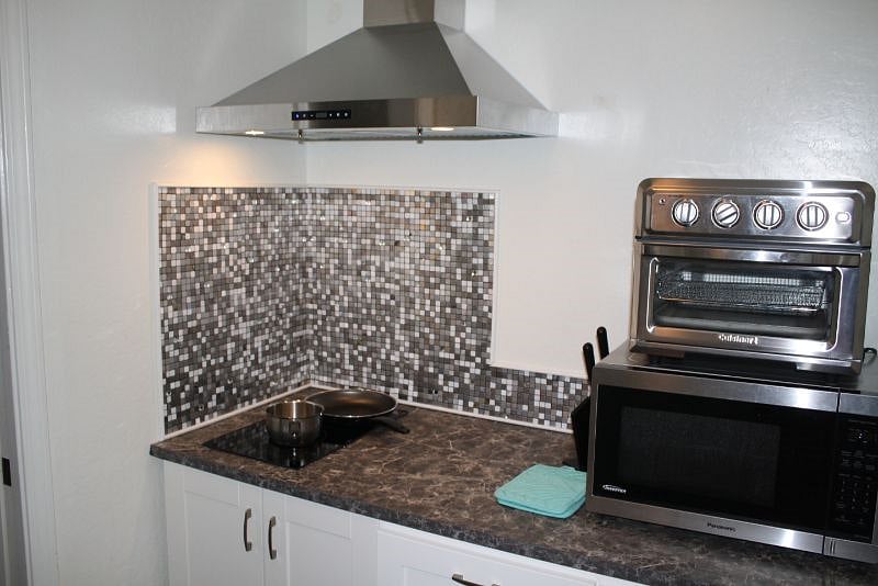 Cooking area with stove, microwave, and toaster oven.