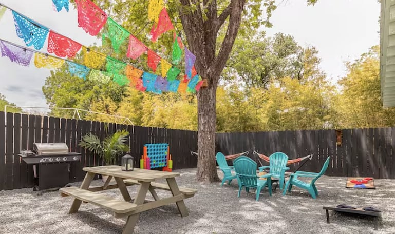 Shaded backyard with picnic table, chairs and grill.