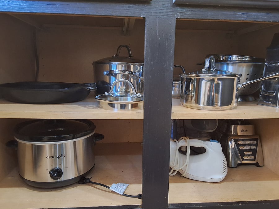 kitchen small appliances including crockpot and stainless steel and cast iron pots and pans