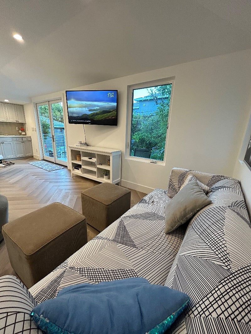 Main Sitting Area with SmartTV, bookcase, and light from french doors and picture window.