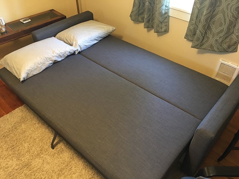 Full size fold out couch with bedding and mattress pad in storage area underneath.
