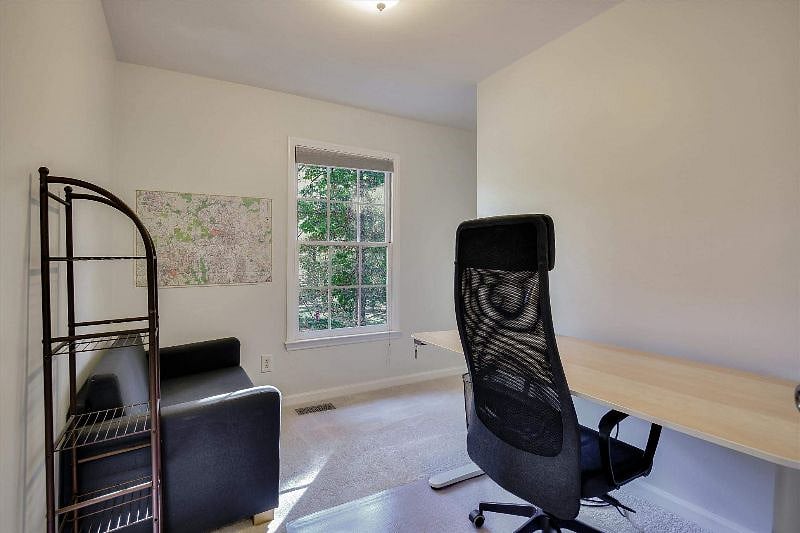 Small office with sit/stand desk and comfortable chair.