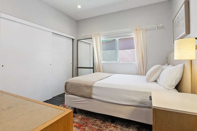 Bedroom with queen sized bed, closet, dresser and vanity mirror.