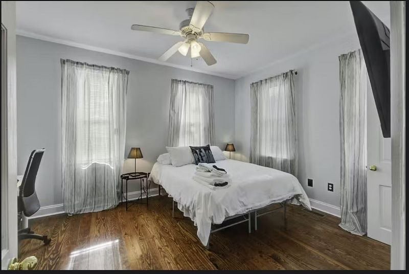 Quiet ground-floor rear bedroom featuring a comfortable Queen bed, a dedicated workspace, a Smart TV, and easy access to a shared bathroom.