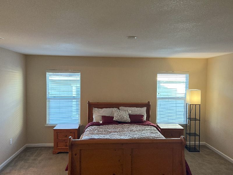 Junior Master bedroom furnished with a queen bed, night stands, and standing lamp. Private bath and walk-in closet