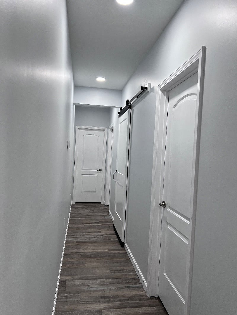 Hallway to master with laundry behind barn door 