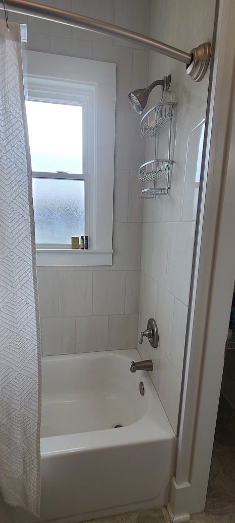 Bathroom with tub/shower combo with tile surround.