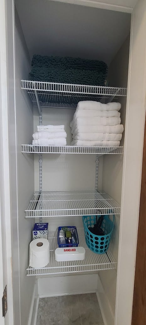 Bathroom closet with towels, bath mats, and amenities.