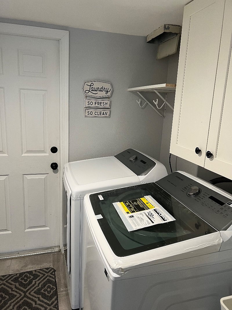 This is the laundry room with brand new washer and dryer and a sink.