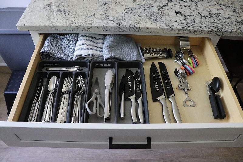Fully equipped kitchen with utensils, measuring cups, knives, tongs, kitchen shears, can opener, and wine opener.