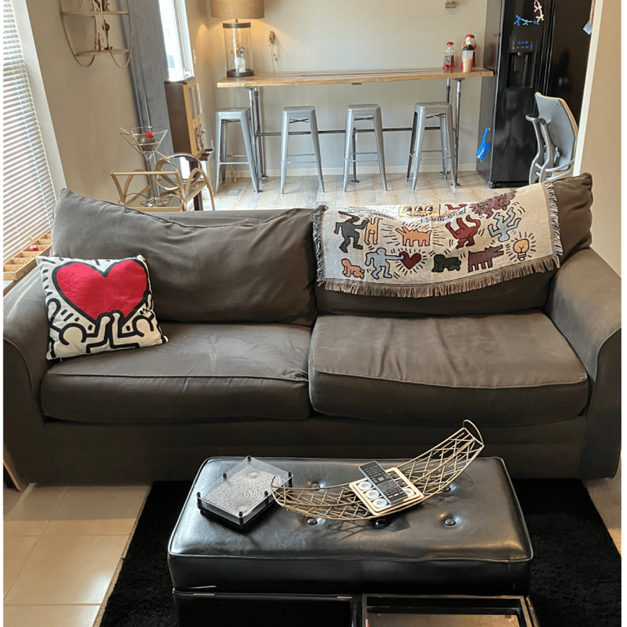 View of couch in living room with the kitchen in the background
