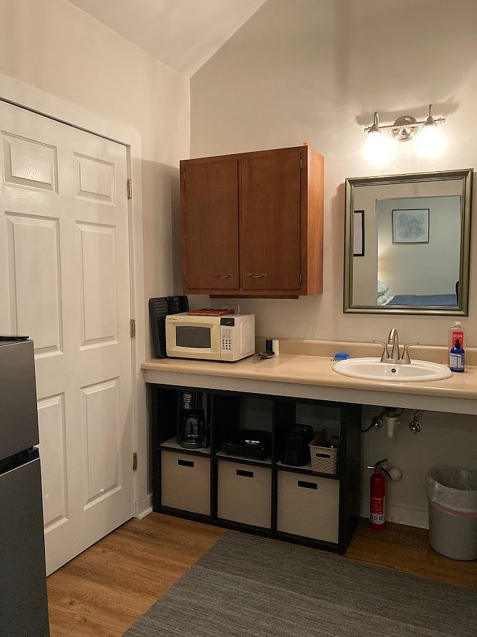 Kitchenette with basic amenities, including expanded mini-fridge with freezer, hot plate, microwave, toaster, coffee maker, dishes, pots, pans.