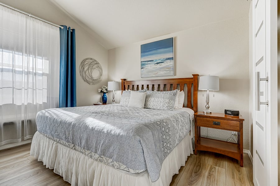 The master bedroom features a plush Saatva king bed as its centerpiece. The bed promises a restful night's sleep with its high-quality, supportive mattress. Large windows flood the room with natural light and creating a bright, airy atmosphere.