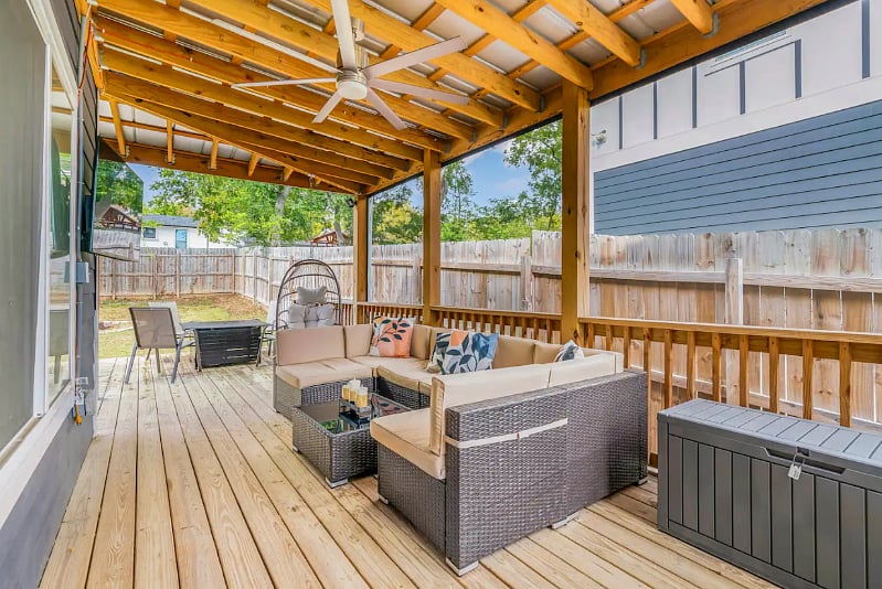 Large fenced in backyard with Outdoor Patio equipped patio furniture, 50" Smart TV, Fire Pit, Outdoor Grill, and Fire Table. 