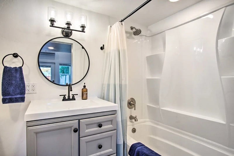 Full bathroom with shower/tub combo, large vanity with storage and a shelf for linens/towels. 