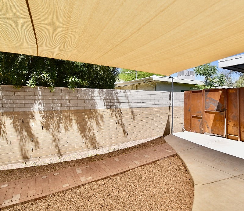 The tiny home is located in a fully enclosed backyard. This unit has a brick walkway that connects the unit from the porch to the side fence.  