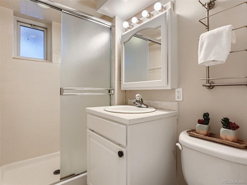 Bathroom with standup shower, medicine cabinet, and several towel racks.