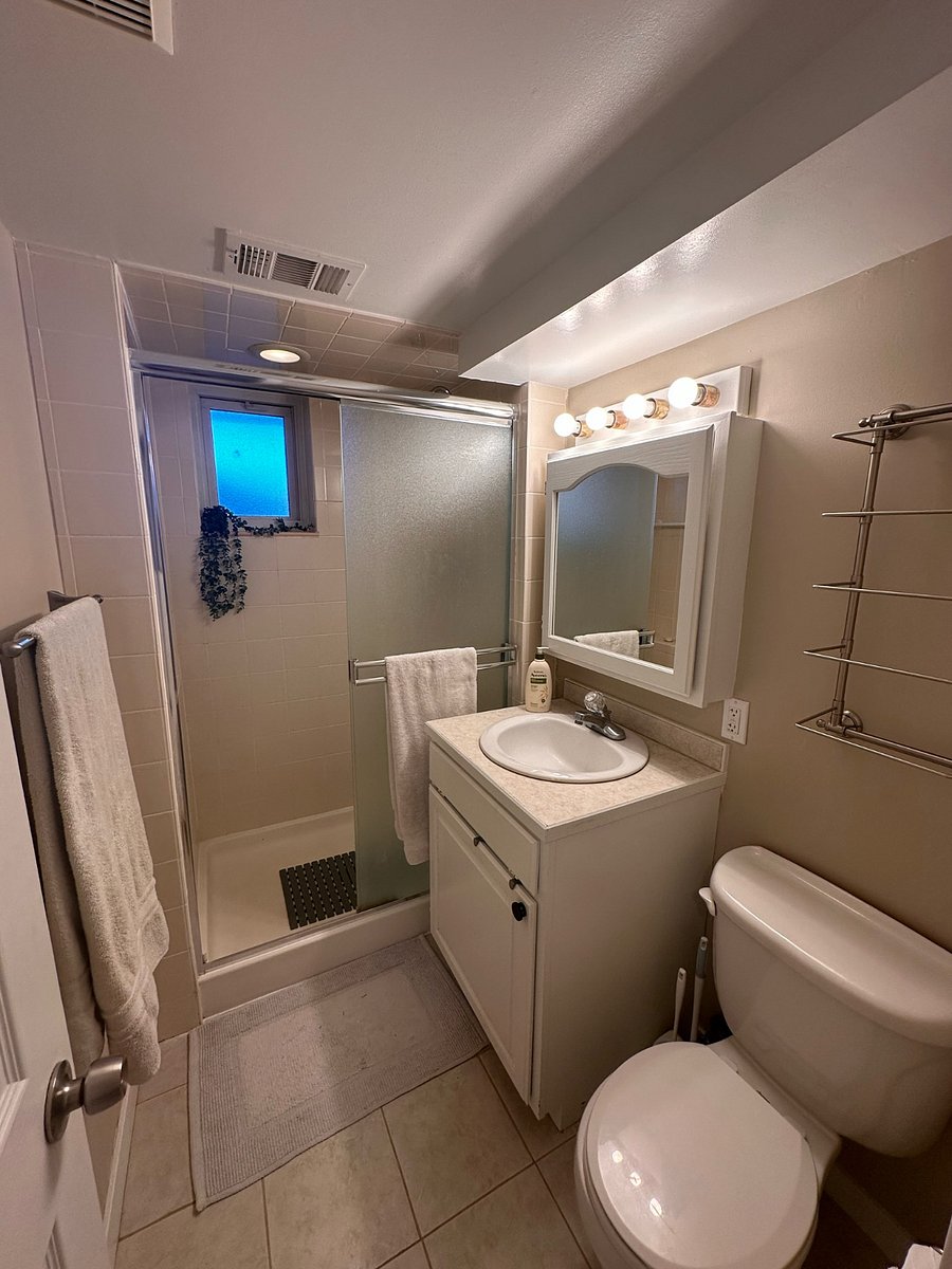 Bathroom with standup shower, medicine cabinet, and several towel racks.