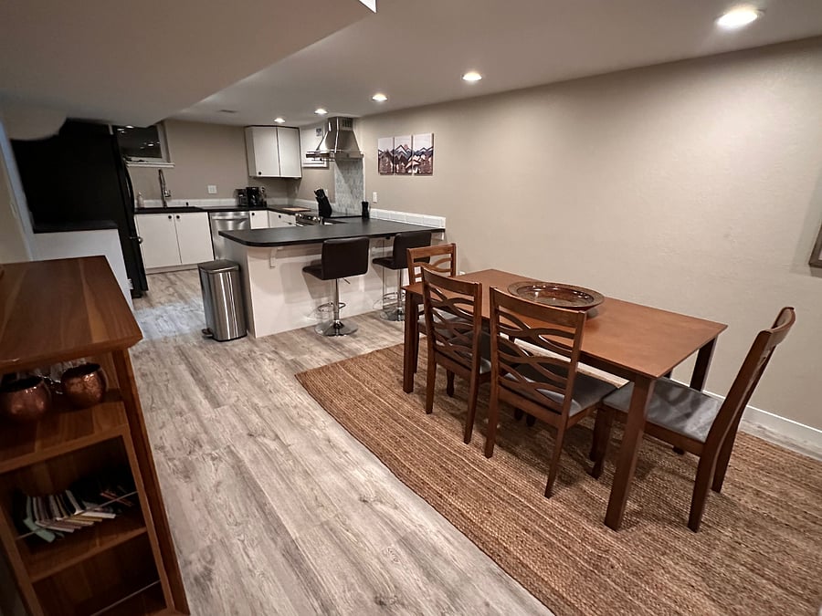 Dining room with fully stocked bar cart and table for six and view into adjacent kitchen area.
