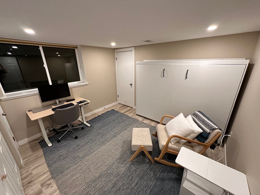 Office/2nd bedroom w/ sit-stand desk, 27" 4K Dell Monitor, Dell docking station, bluetooth keyboard and mouse, murphy bed (in folded up position) and rocking/reading chair with nightstand.