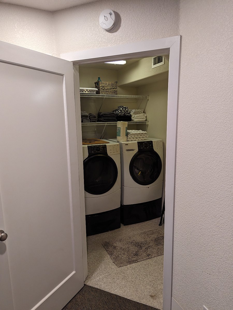 Washer/Dryer room, conveniently tucked away in a corner with a closable door. You can fully stand up in here and there is lighting and storage space.