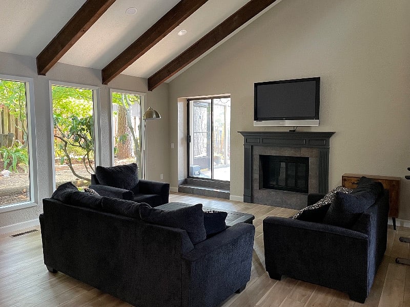 Very large living room with widescreen tv, AppleTV, seating for 6, view of private backyard, and access to spacious sunroom.