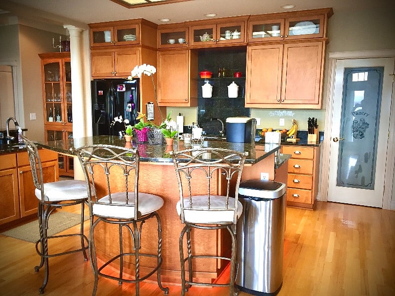 Kitchen island with three chair, eating bar, and one oven on the other side.
