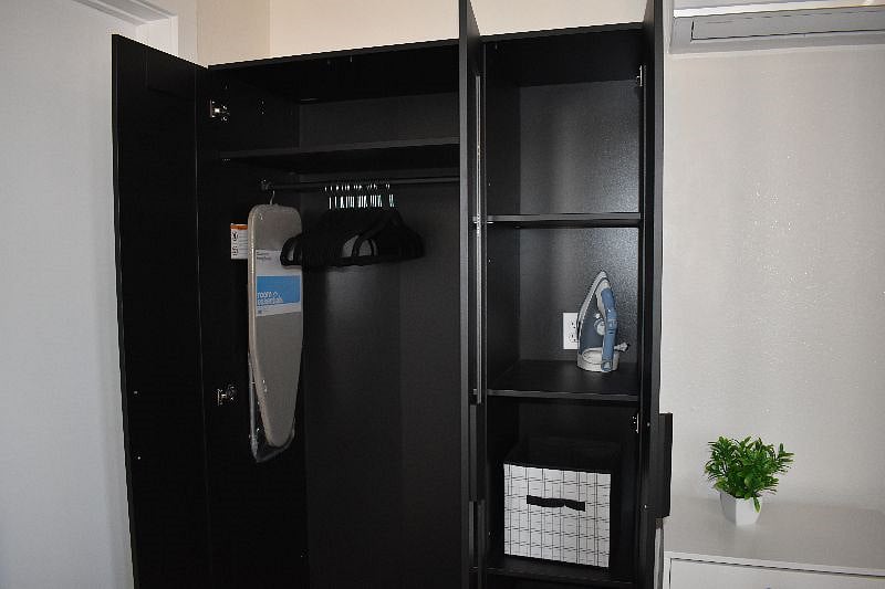 Spacious wardrobe with clothes hangers, ironing board and iron. 
