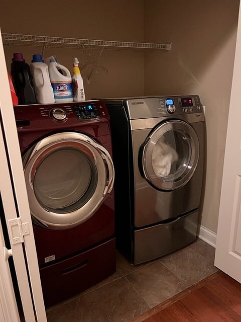 Full washer and dryer with overhead shelf and hanging space above. located at the top of stairs to the right before the master