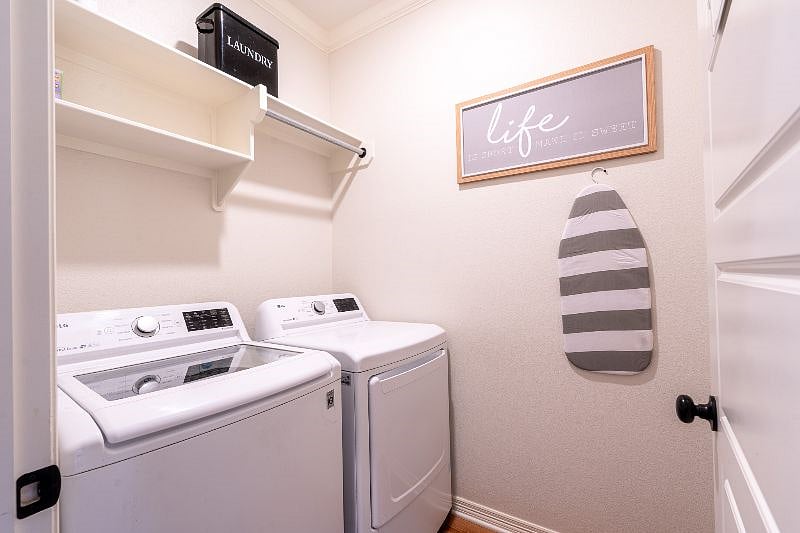 Laundry room with full size washer and dryer, iron and mini ironing board, and starter set of laundry pods.
