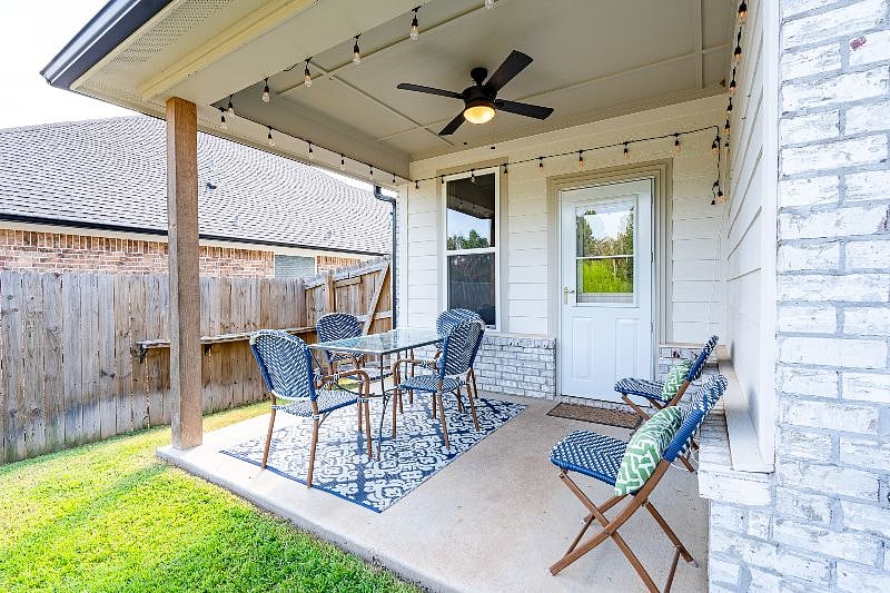 The back patio includes a charming table and seating for six, hanging lantern lights, and a ceiling fan.