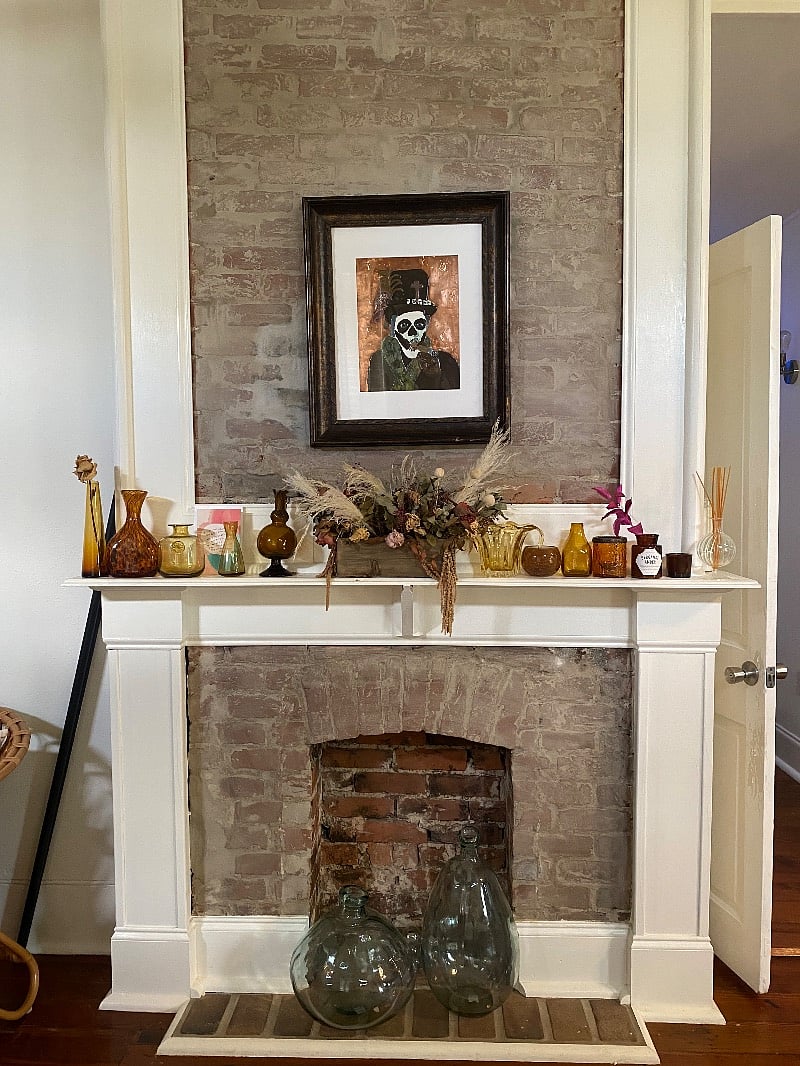 Baron Samedi by K Elizabeth (artist) hangs above the styled mantle