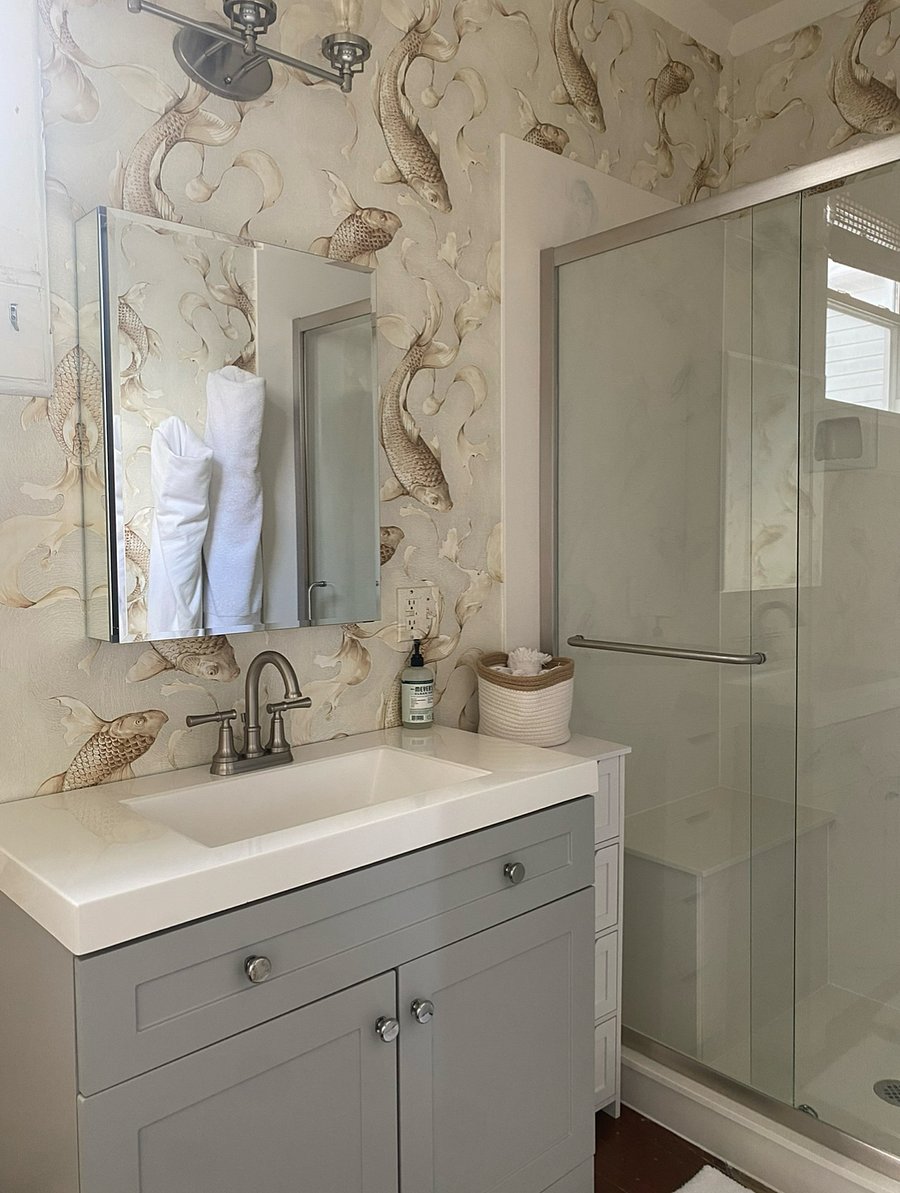 Bathroom attached to primary bedroom with beautiful wallpaper and new shower. 