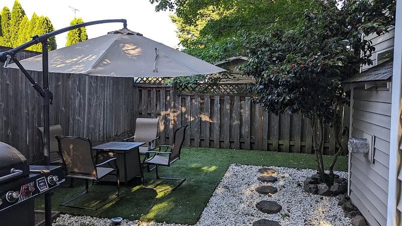 Enjoy outdoor living in our backyard oasis with a patio table, umbrella, and BBQ grill for delightful gatherings.