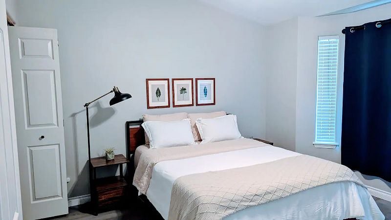 Unwind in the spacious first queen bedroom with a comfortable queen bed, abundant natural light, and a stunning vaulted ceiling.