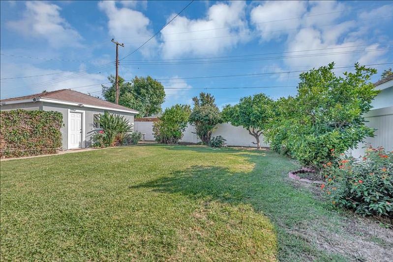Backyard with garage and patio access, lemon, grapefruit, orange trees, and beautiful rose bushes a serene outdoor haven.
