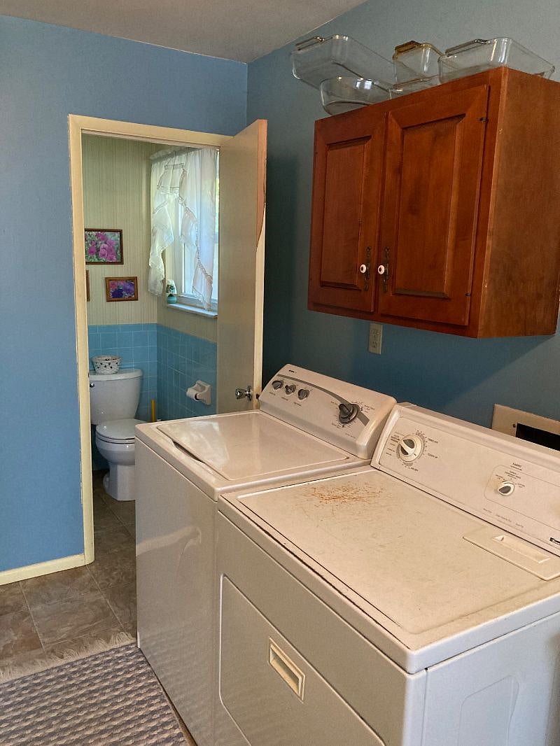 Washing machine and dryer adjacent to half bath. New linoleum floor.