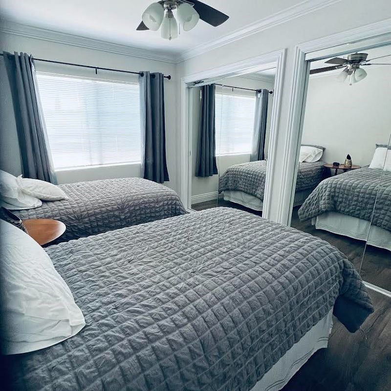 Second bedroom with two twin beds and mirrored closet with interior dresser.