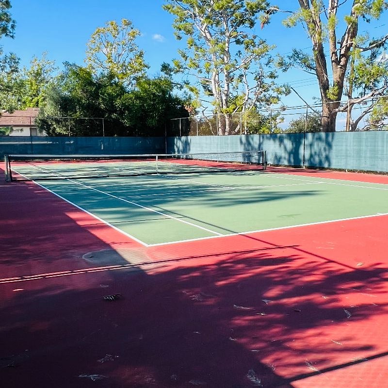 Tennis court next to pool.