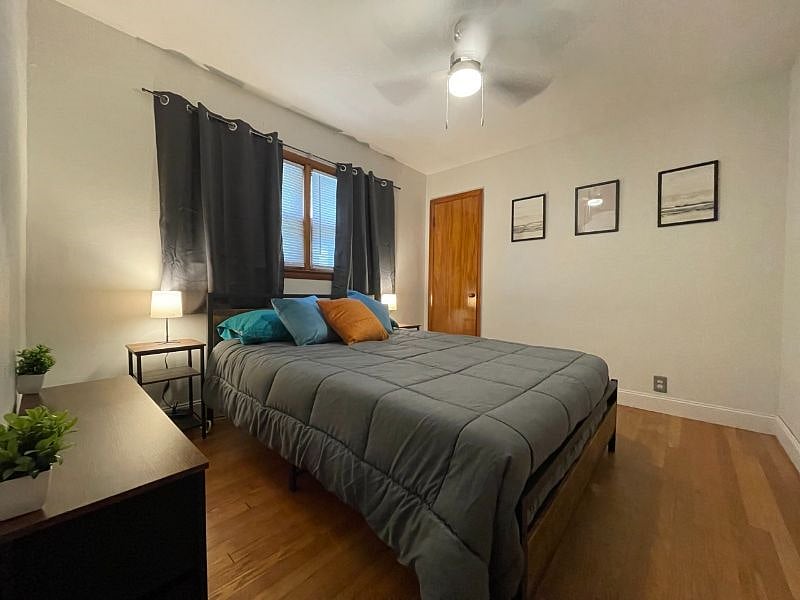Bedroom 1 with queen bed, dresser, night stands, lamps, usb charger and outlet extender, ceiling fan, black out curtains, and closet.