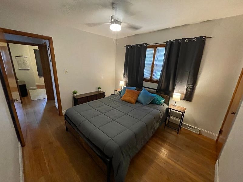Bedroom 1 with queen bed, dresser, night stands, lamps, usb charger and outlet extender, ceiling fan, black out curtains, and closet.