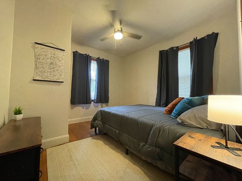 Bedroom 2 with queen bed, dresser, night stand, lamp, usb charger and outlet extender, ceiling fan, black out curtains, and closet.