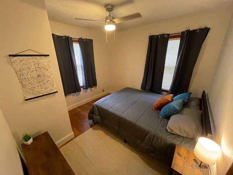 Bedroom 2 with queen bed, dresser, night stand, lamp, usb charger and outlet extender, ceiling fan, black out curtains, and closet.