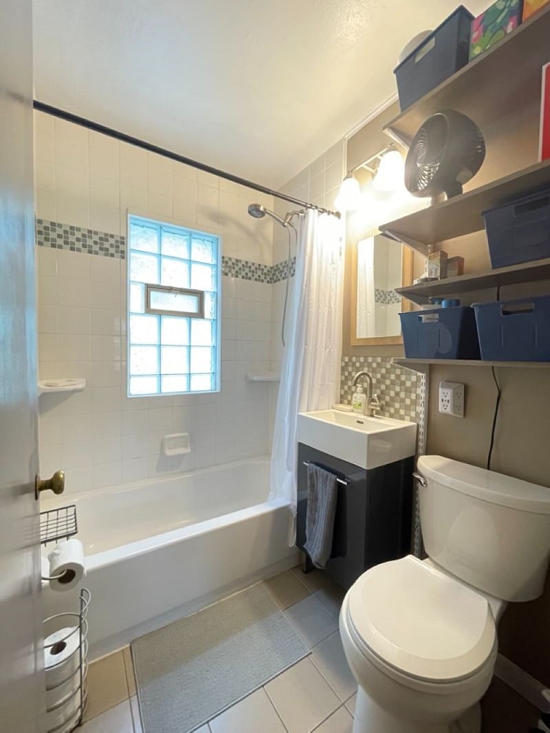 Bathroom with removable shower head, fan, hair dryer, shower curtains, and starter pack for bath essentials (shampoo/conditioner, soap, deodorant, first aid, etc).