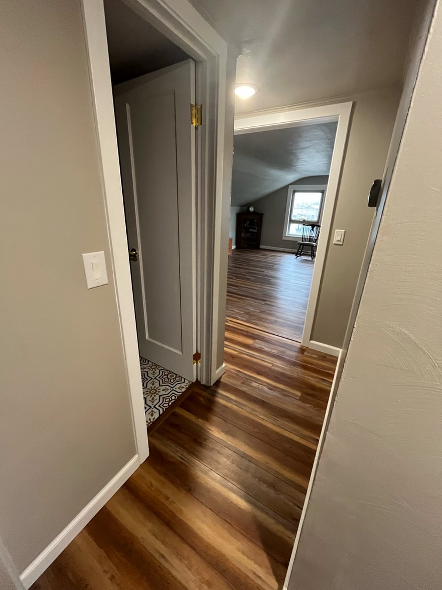 Hallway from kitchen heading into living room. Bathroom is the door on the left