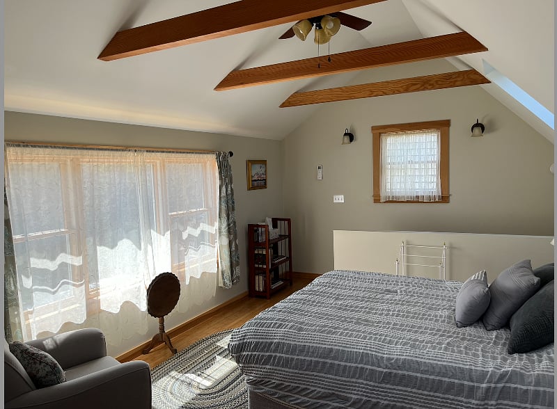 Bedroom with windows that look out on wooded back yard