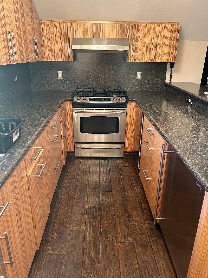 Kitchen. There is a fridge and a freezer separate from one another pictured to the right, a stove, oven, sink, microwave and plenty of counter space along with a bar top with two bar stools.