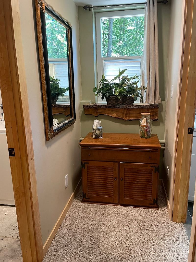 Bedroom window and entry into the bathroom. Linen closet with towels under the window.